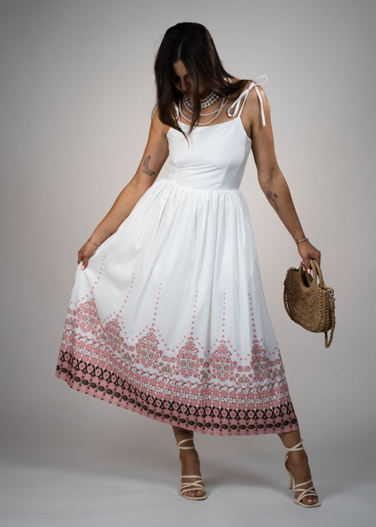 White maxi midi dress with pink flowers at the hem and ties on the shoulders. Elegant and feminine, perfect for a stylish summer look